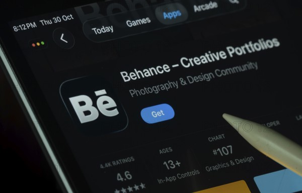 Dhaka, Bangladesh- 30 Oct 2025: Behance app displayed on a iPad screen in dark mode with a digital pen pointing at it