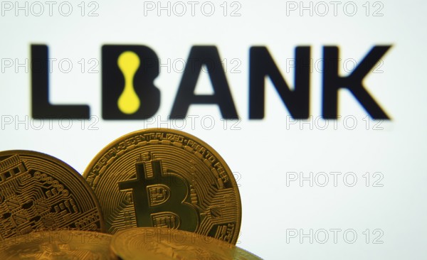 Dhaka, Bangladesh- 03 Sep 2025: Close-up of Bitcoin coins with the LBank logo visible on a screen in the background
