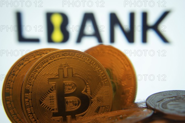 Dhaka, Bangladesh- 03 Sep 2025: Close-up of Bitcoin coins with the LBank logo visible on a screen in the background