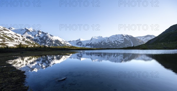 Mountain peaks with Portage Glacier glacier and snow reflected in Divide Lake mountain lake in evening light, Portage Pass Trail, Whittier, Alaska, USA
