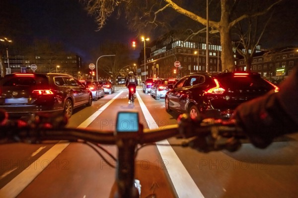 Cycling in the city, in the dark, in the evening, cycling on a bike lane, marked in red, Huyssenallee, in downtown Essen, North Rhine-Westphalia, Germany