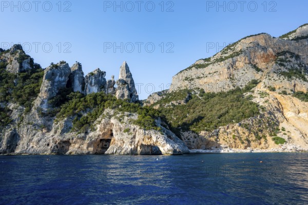 Picturesque rocky coast, cliffs with caves in the morning light, L'Aguglia rock peak, blue sea and Cala Goloritzé beach, Golfo di Orosei, Baunei, Sardinia, Italy