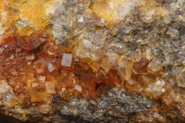 Shiny crystals of blue and orange color can be seen in this mineral formation. They are sparkling and show interesting textures in a natural setting