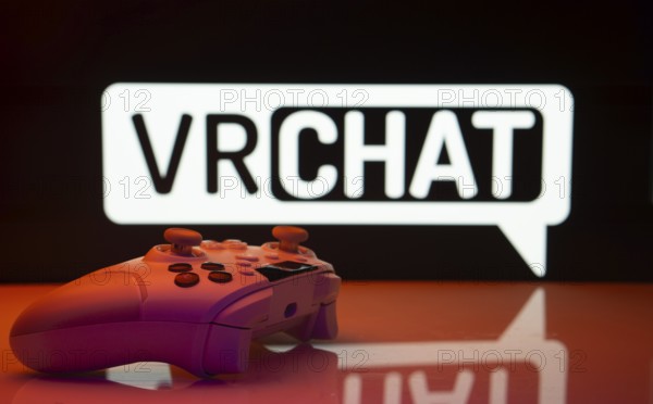 Dhaka, Bangladesh- 14 Nov 2025: A close-up of a white gamepad with the VRChat seen on screen in the background