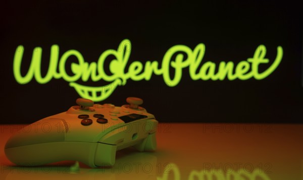 Dhaka, Bangladesh- 14 Nov 2025: A close-up of a white gamepad with the WonderPlanet Inc seen on screen in the background