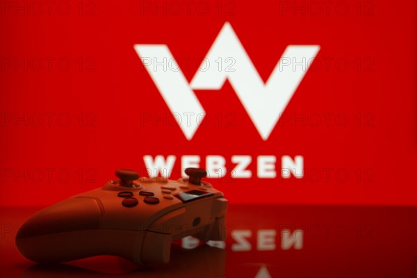 Dhaka, Bangladesh- 14 Nov 2025: A close-up of a white gamepad with the Webzen seen on screen in the background