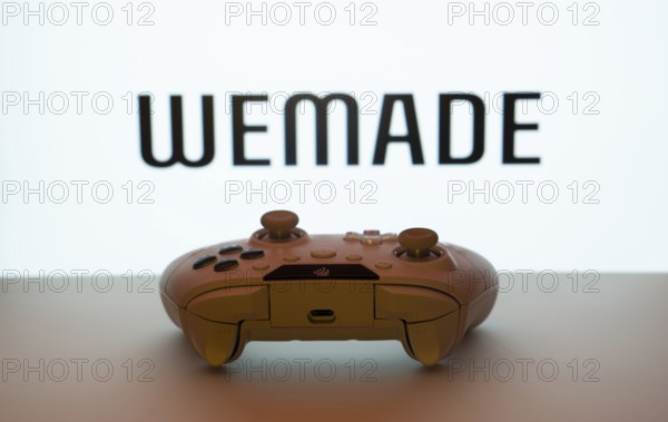 Dhaka, Bangladesh- 14 Nov 2025: A close-up of a white gamepad with the WeMade Entertainment seen on screen in the background
