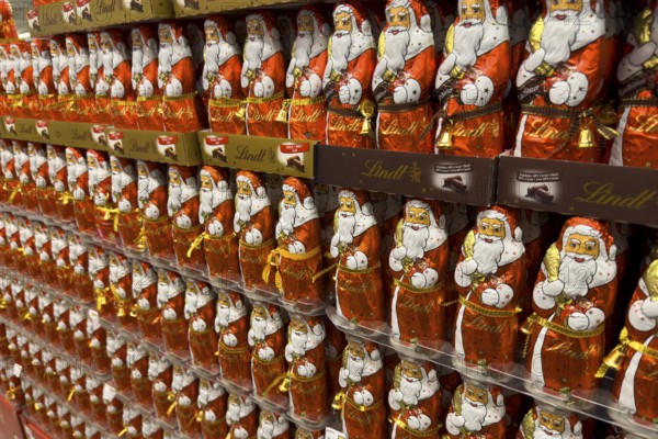 Display on the shelf of chocolate Santa Claus chocolate Santa Claus Santa Claus Santa Claus Santa Claus chocolate Santa Claus chocolate Santa Claus chocolate lice Santa Claus chocolate lice Santa Claus in color red of red staniol paper made of chocolate arranged like army of Santa Claus, Germany