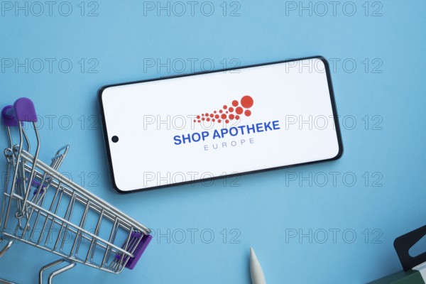 Dhaka, Bangladesh- 21 Nov 2025: Smartphone displaying Shop Apotheke logo with shopping cart on a blue background