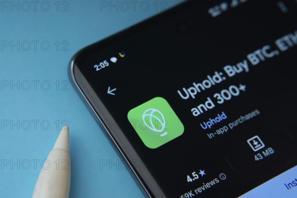 Dhaka, Bangladesh- 19 Sep 2025: On a blue surface, a smartphone displays the Uphold app within the Google Play Store