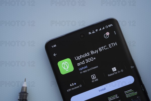 Dhaka, Bangladesh- 19 Sep 2025: On a blue surface, a smartphone displays the Uphold app within the Google Play Store
