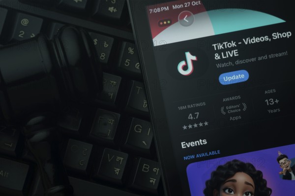 Dhaka, Bangladesh- 28 Oct 2025: An iPad displaying the TikTok app against a judge's gavel and dark keyboard background