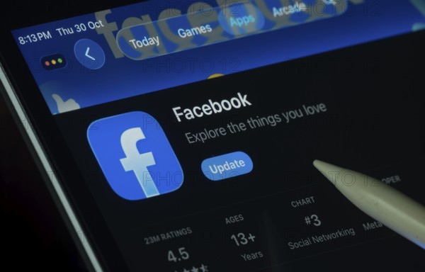 Dhaka, Bangladesh- 30 Oct 2025: Facebook app displayed on a iPad screen in dark mode with a digital pen pointing at it