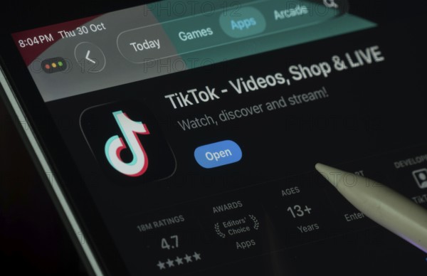 Dhaka, Bangladesh- 30 Oct 2025: TikTok app displayed on a iPad screen in dark mode with a digital pen pointing at it