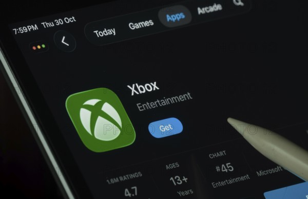 Dhaka, Bangladesh- 30 Oct 2025: Xbox app displayed on a iPad screen in dark mode with a digital pen pointing at it