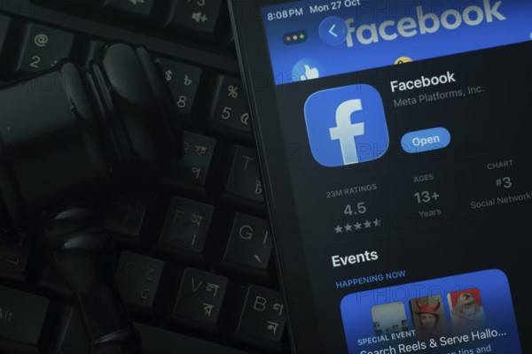 Dhaka, Bangladesh- 28 Oct 2025: An iPad displaying the Facebook app against a judge's gavel and dark keyboard background