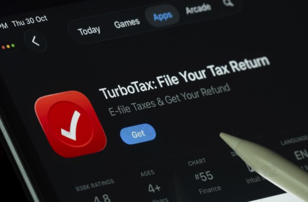 Dhaka, Bangladesh- 30 Oct 2025: TurboTax app displayed on a iPad screen in dark mode with a digital pen pointing at it