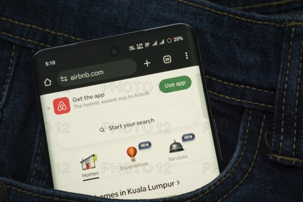 Dhaka, Bangladesh- 21 Nov 2025: A smartphone displaying the Airbnb web interface peeks out of a denim pocket