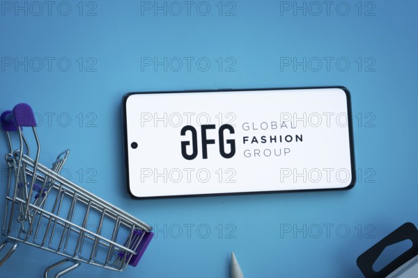 Dhaka, Bangladesh- 21 Nov 2025: Smartphone displaying Global Fashion Group logo with shopping cart on a blue background