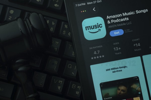 Dhaka, Bangladesh- 21 Nov 2025: An iPad displaying the Amazon Music app against a judge's gavel and dark keyboard background