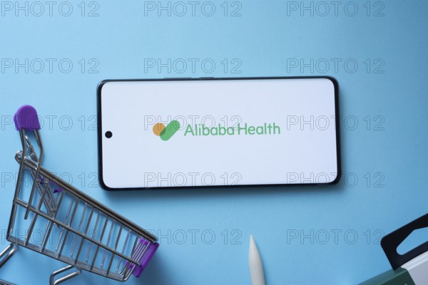Dhaka, Bangladesh- 21 Nov 2025: Smartphone displaying Alibaba Health logo with shopping cart on a blue background