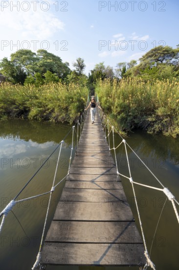 Toruist on the Kavango River, suspension bridge at Camp Kwando, Zambezi region, Caprivi Strip, Namibia