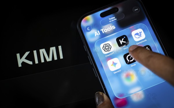 In this photo illustration, a person uses the Kimi AI chatbot on a smartphone while the KIMI logo is displayed on a screen in the background, in New Delhi, India on 20 November 2025. Kimi AI is a Chinese artificial intelligence chatbot and assistant developed by Moonshot AI, a fast-growing tech company in China