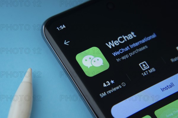 Dhaka, Bangladesh- 29 May 2025: On a blue surface, a smartphone displays the WeChat app within the Google Play Store