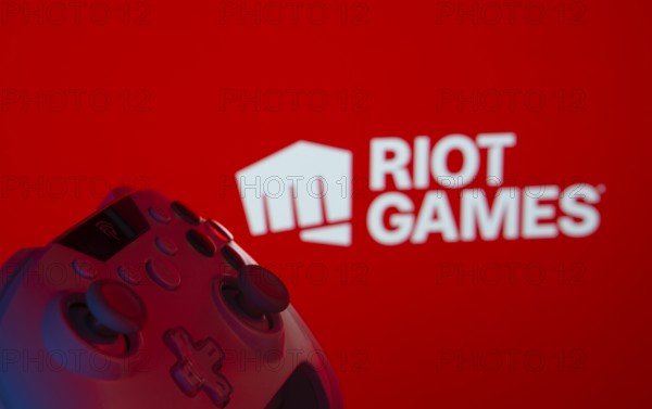 Dhaka, Bangladesh- 14 Nov 2025: A close-up of a gamepad with the Riot Games seen on screen in the background