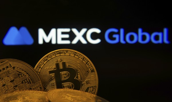Dhaka, Bangladesh- 03 Sep 2025: Close-up of Bitcoin coins with the MEXC Global logo visible on a screen in the background