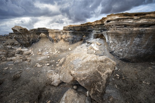Eroded rock formations in volcanic landscape with dramatic cloudy skies, Ciudad Estratificada or Los Roferos, Antigua Rofera de Teseguite, Lanzarote, Canary Islands, Spain