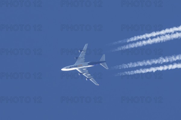 Boeing 747 jumbo jet cargo aircraft of Atlas air airlines flying in a blue sky with contrails or vapour trails behind, England, United Kingdom