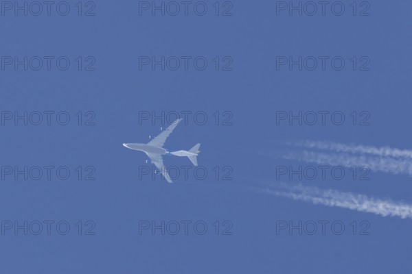Boeing 747 jumbo jet cargo aircraft flying in a blue sky with contrails or vapour trails behind, England, United Kingdom