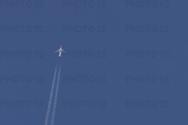Boeing 737 jet passenger aircraft of Norwegian Air airlines flying in a blue sky with contrails or vapour trails behind, England, United Kingdom