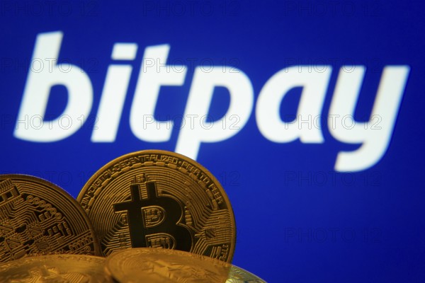 Dhaka, Bangladesh- 26 Aug 2025: Close-up of Bitcoin coins with the bitpay logo visible on a screen in the background