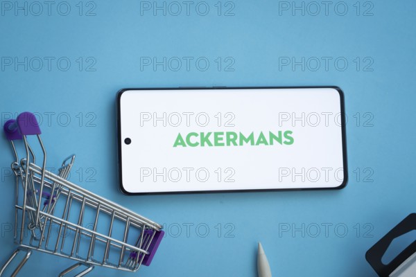 Dhaka, Bangladesh- 03 July 2025: Smartphone displaying Ackermans logo with shopping cart on a blue background