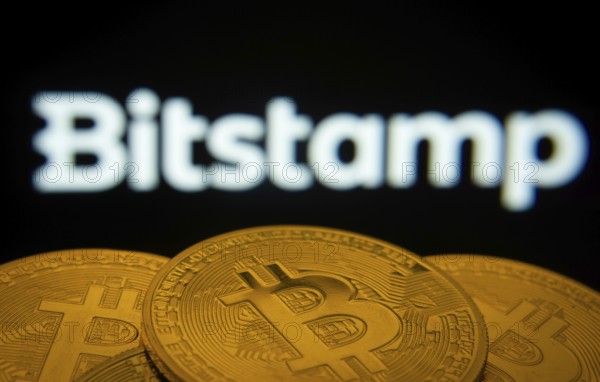 Dhaka, Bangladesh- 03 Sep 2025: Close-up of Bitcoin coins with the Bitstamp logo visible on a screen in the background