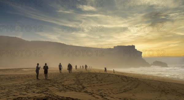 Tourists watch the waves of the Atlantic on the rocky plateau of Sito, also known as Forte São Miguel, a surfing paradise with monster waves in the months of November to February, Nazaré, Portugal