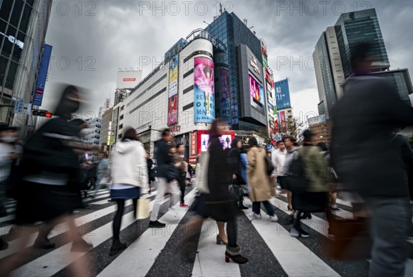 Crowd crossing zebra crossing on a large intersection, motion blur, back modern houses with colorful neon signs, long exposure, Shibuya Crossing, Shibuya, Tokyo, Japan