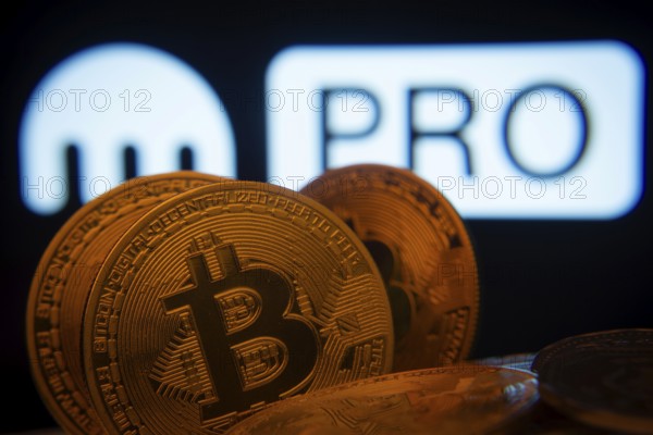 Dhaka, Bangladesh- 01 Nov 2025: Close-up of Bitcoin coins with the Kraken Pro logo visible on a screen in the background
