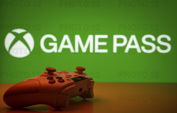 Dhaka, Bangladesh- 19 Sep 2025: A close-up of a white gamepad with the Xbox Game Pass seen on screen in the background