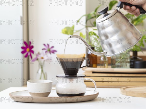 Barista preparing filter coffee using a modern kettle and a ceramic dripper