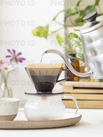 Hot water being poured from a modern kettle into a coffee filter, brewing a fresh cup of coffee