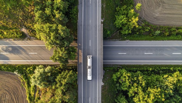 Petrol cargo truck lorry tanker driving on highway hauling oil products at sunrise, wide hilly landscape, AI generated