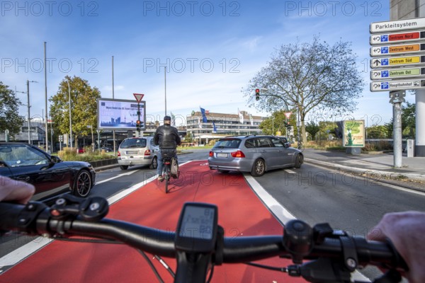 Riding a bike in a bike lane, marked in red to attract the attention of motorists, between 2 lanes, Huyssenallee, in front of Europaplatz, in the city centre of Essen, North Rhine-Westphalia, Germany