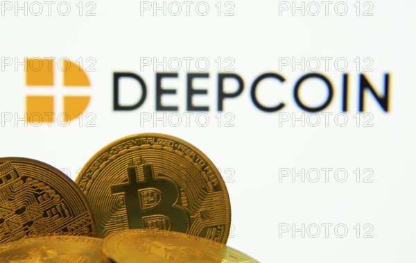 Dhaka, Bangladesh- 03 Oct 2025: Close-up of Bitcoin coins with the Deepcoin logo visible on a screen in the background