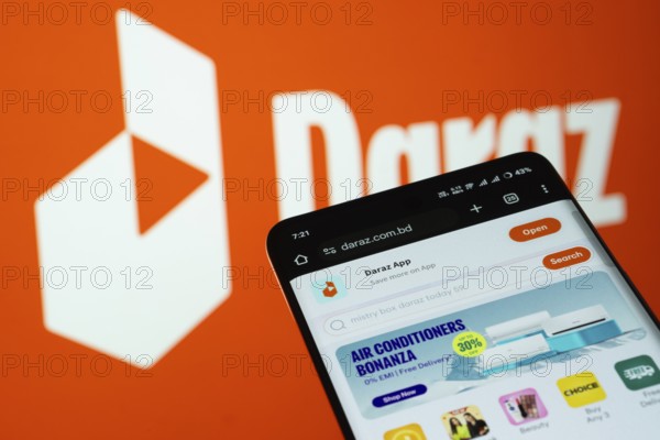 Dhaka, Bangladesh- 03 Oct 2025: Smartphone displaying Daraz web interface against Daraz logo background