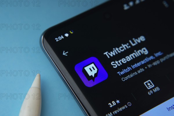 Dhaka, Bangladesh- 30 Sep 2025: On a blue surface, a smartphone displays the Twitch app within the Google Play Store