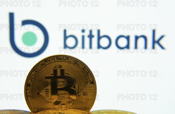 Dhaka, Bangladesh- 02 June 2025: Close-up of Bitcoin coins with the bitbank logo visible on a screen in the background