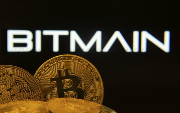 Dhaka, Bangladesh- 15 June 2025: Close-up of Bitcoin coins with the Bitmain logo visible on a screen in the background